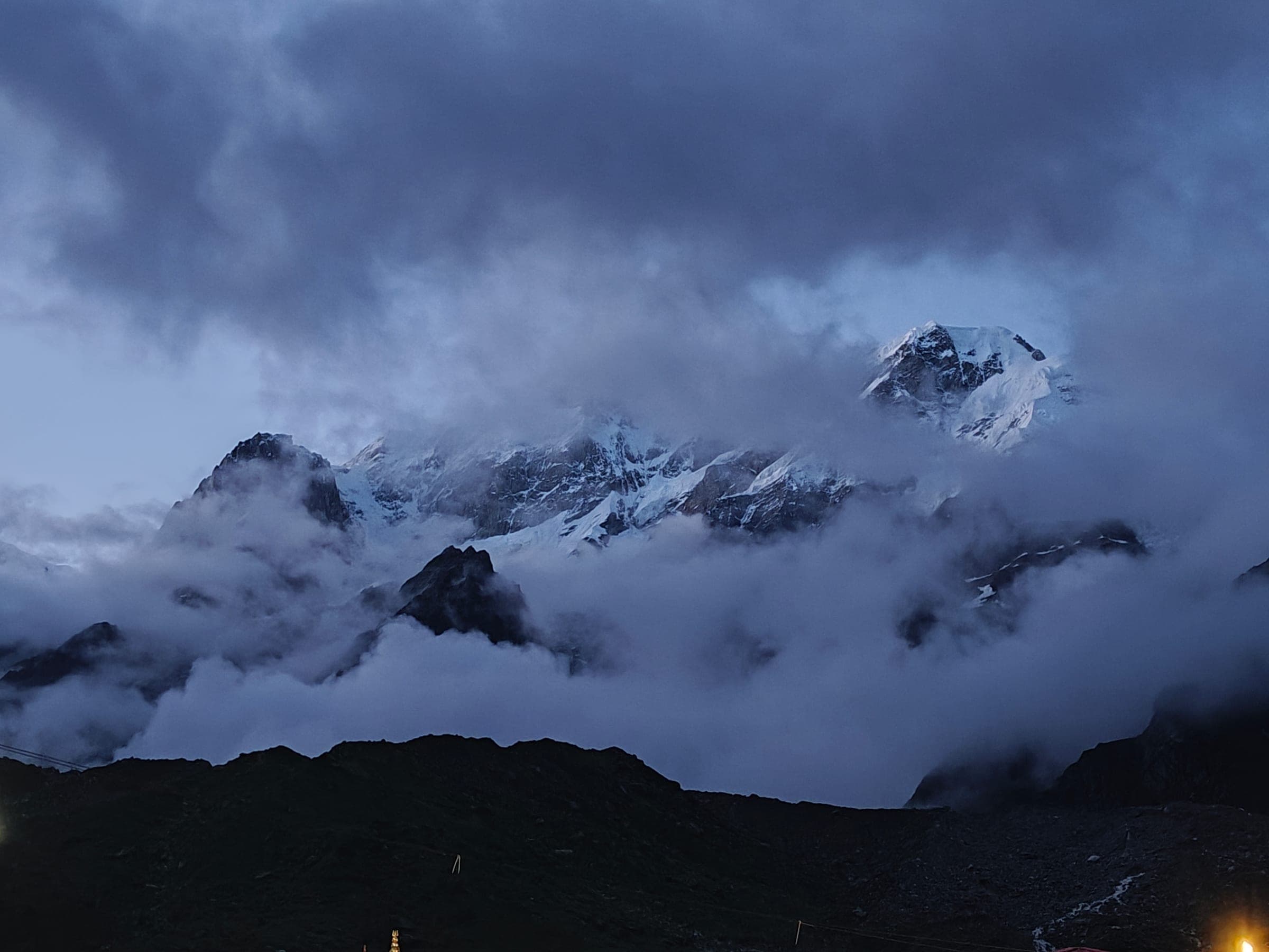 Snow-covered peaks breaking through heavy cloud at dusk.